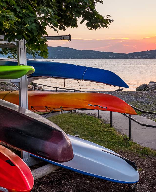 Multi-colored kayaks are stored next to the Hudson River.