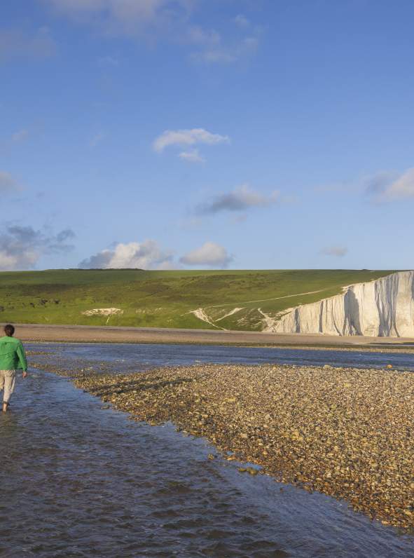 A couple walk in the water at low tide near Seven Sisters