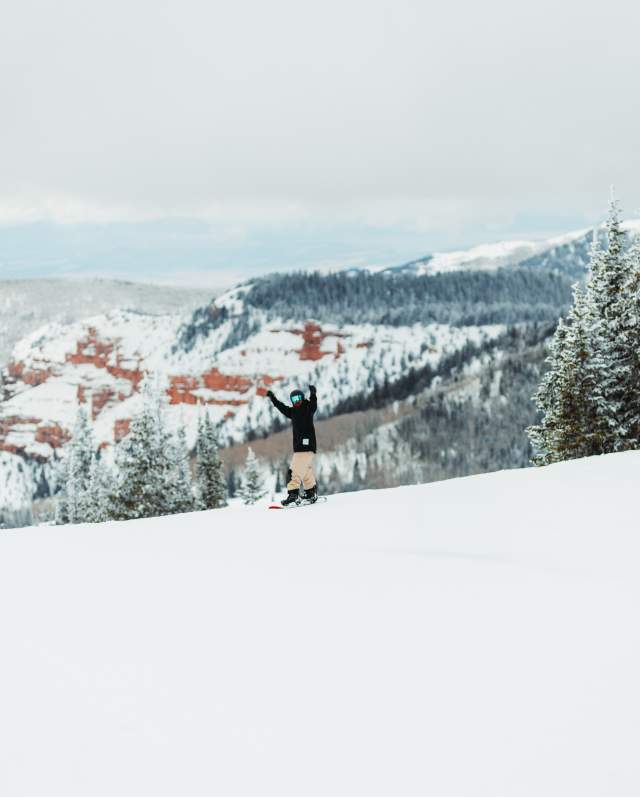 Snowboarding at Brian Head Resort with beautiful red rock in the background.
