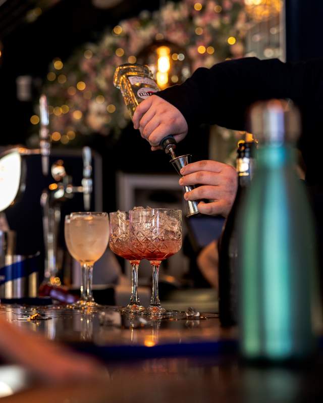 An action shot of a bartender making a cocktail in a cocktail bar