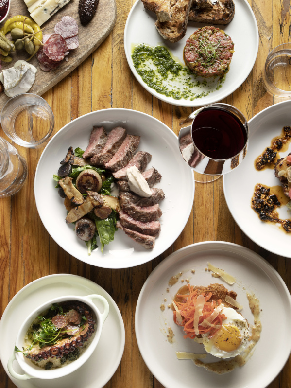 a wide array of food laid out artfully on a wooden table and shot from a birds eye view