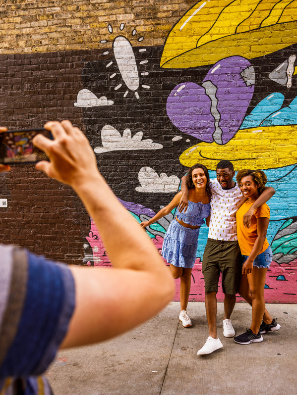 friends taking a picture in front of a colorful mural