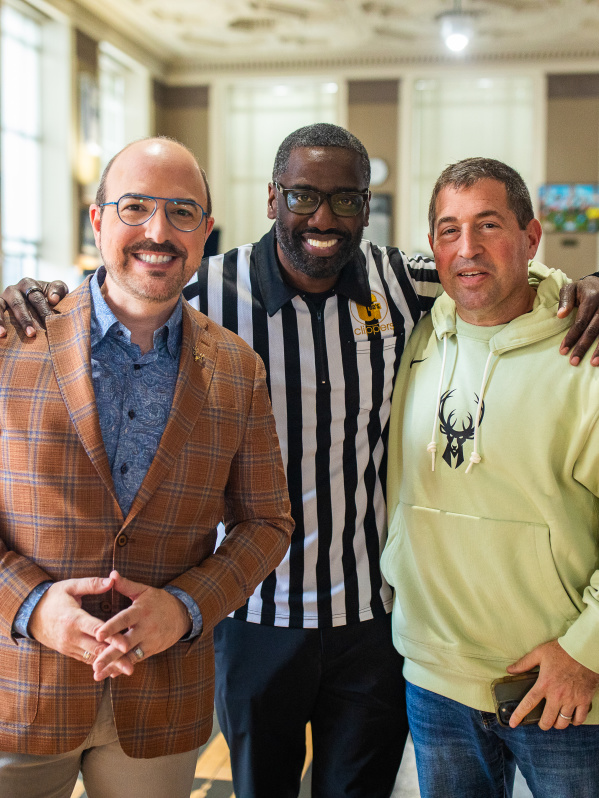 Three men standing together with arms around each other's shoulders at Gee's, smiling at the camera.