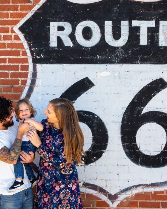 Family posing with their toddler in front of the Route 66 sign in the Britton District