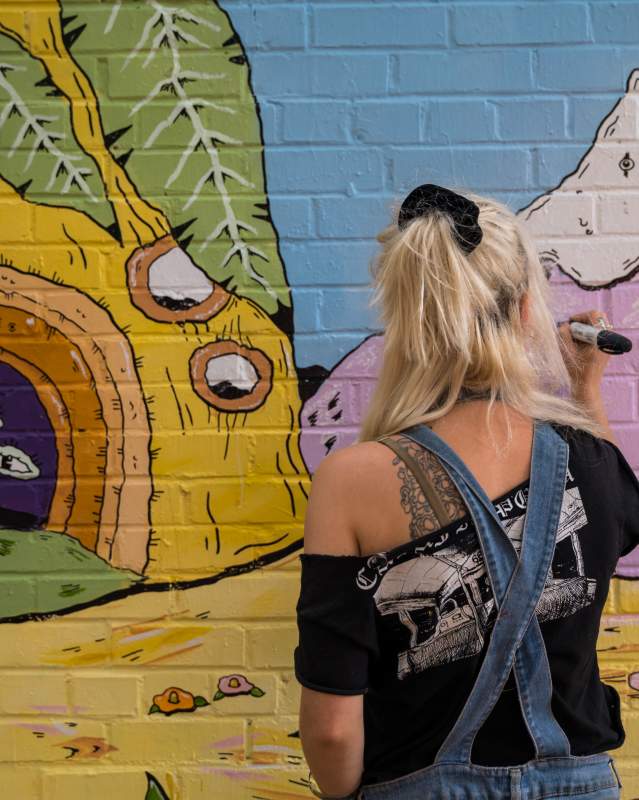 Woman drawing mural on wall