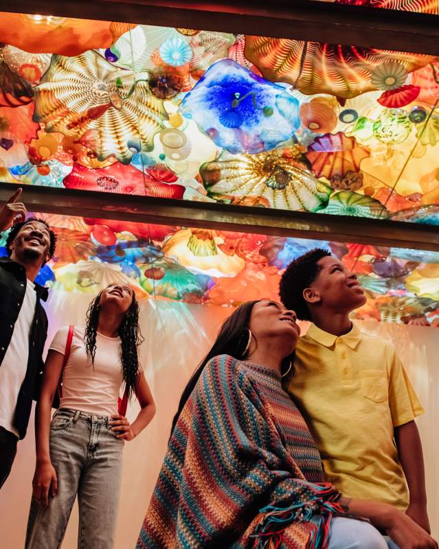 Family of 4 looking at a ceiling of Chihuly glass at the Oklahoma City Museum of Art