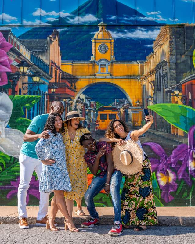 Group of friends pose in front of mural at Cafe Kacao