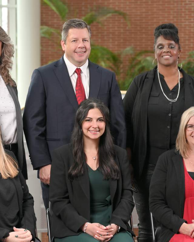 Diverse team of six Akron event planners posed indoors in a bright, modern workspace