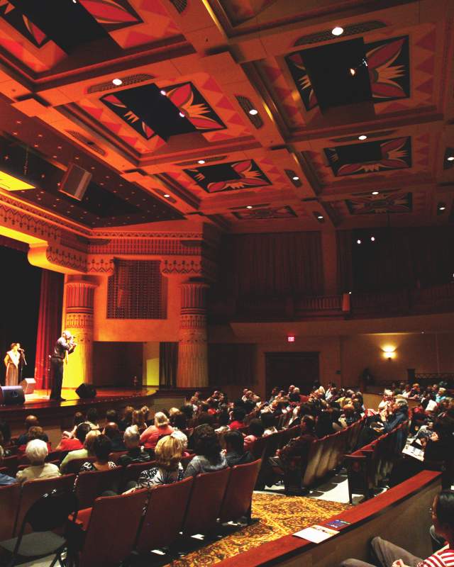 Seated crowd inside the Lincoln Theatre with group of African American singers from the Harlem Gospel Choir on stage