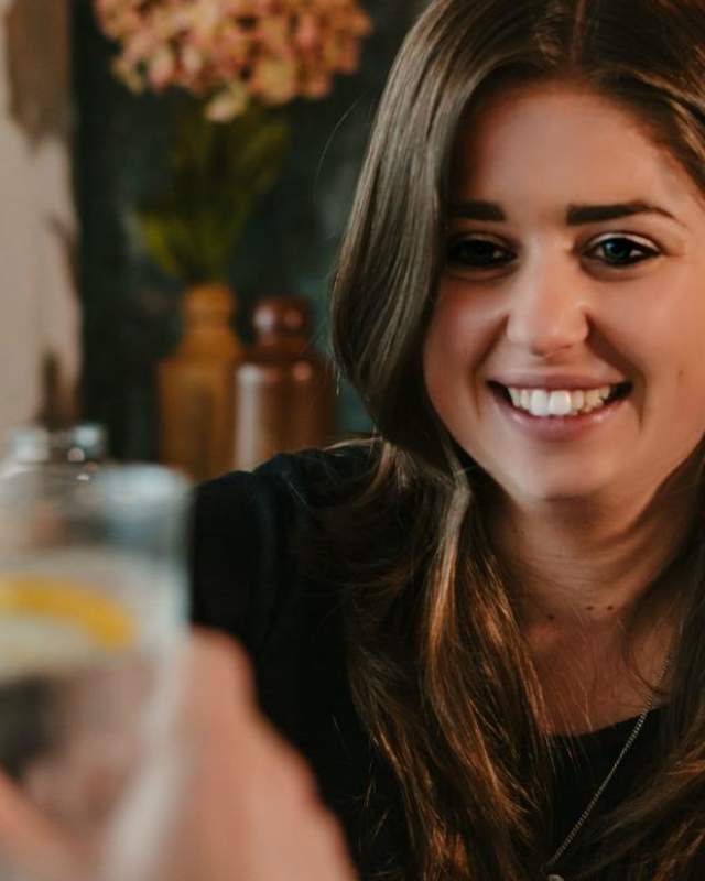 Woman toasting with a drink in a restaurant