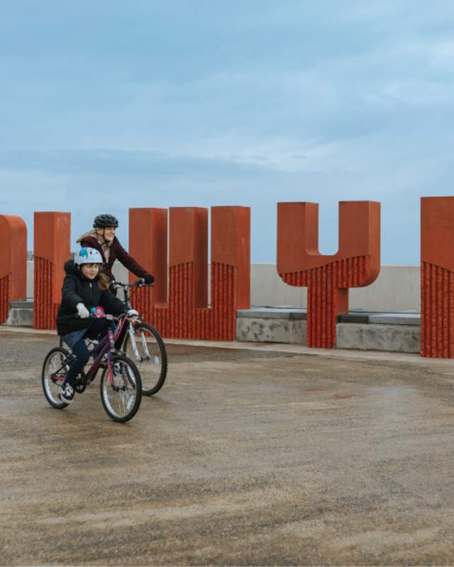 Cyclists going past the Colwyn sign