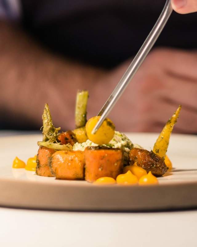 View of a dish being delicately prepared by a chef
