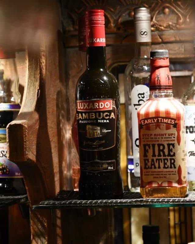 Drinks on display on a shelf above a bar