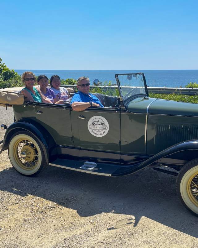 Family taking a joy ride along the coast in an antique car
