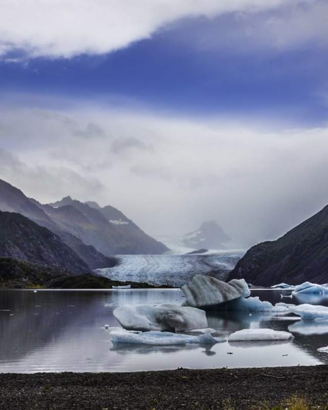 Misty mountains and cloudy sky over chunks of grewingk glacier in the bay