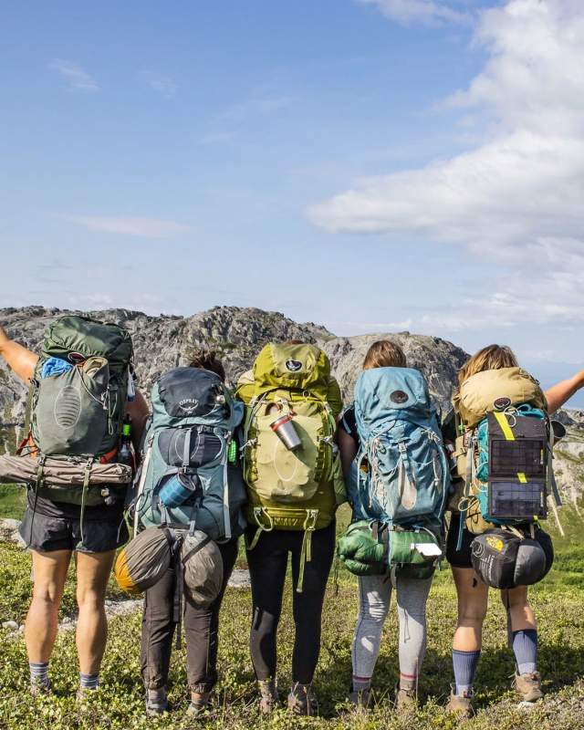 5 friends with backpacks looking over the grass and hills of Kachemak Bay State Park