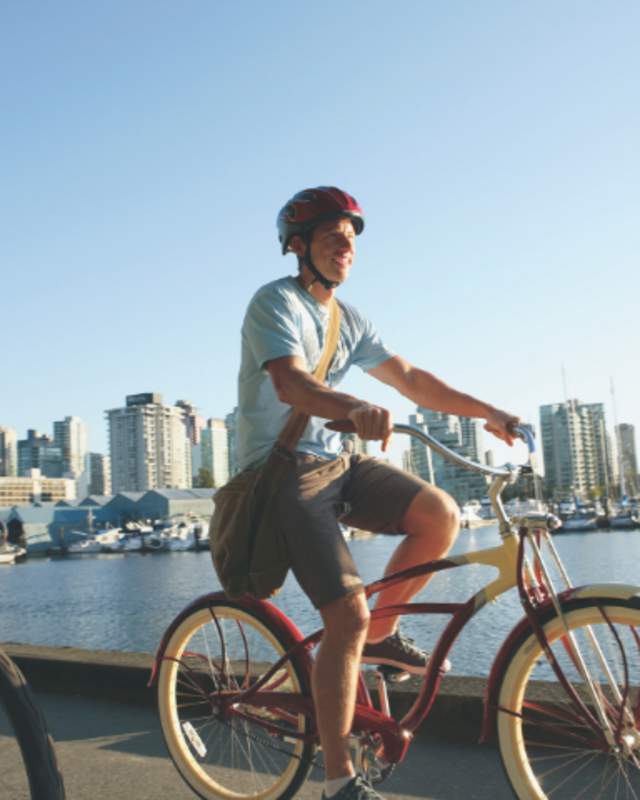 2 men riding bikes with a city and water in the background