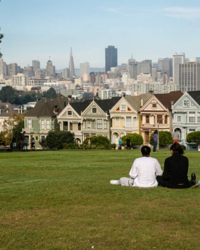 2 people sitting on grass overlooking a city