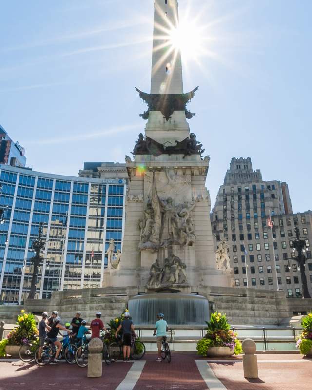 A group touring Monument Circle on bike