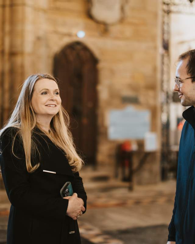 a woman smiles at a tour guide in Boston stump with church walls in background