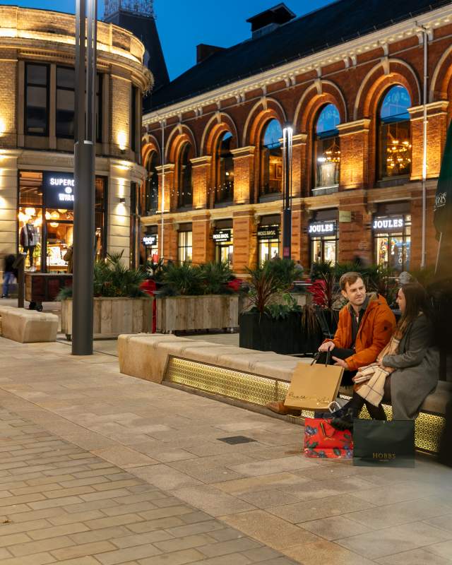 An evening view of the Cornhill Quarter in Lincoln, with a couple shopping in the forefront
