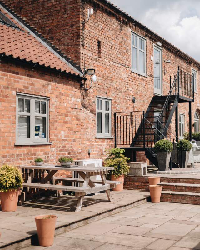 Accommodation exterior with picnic benches and plants