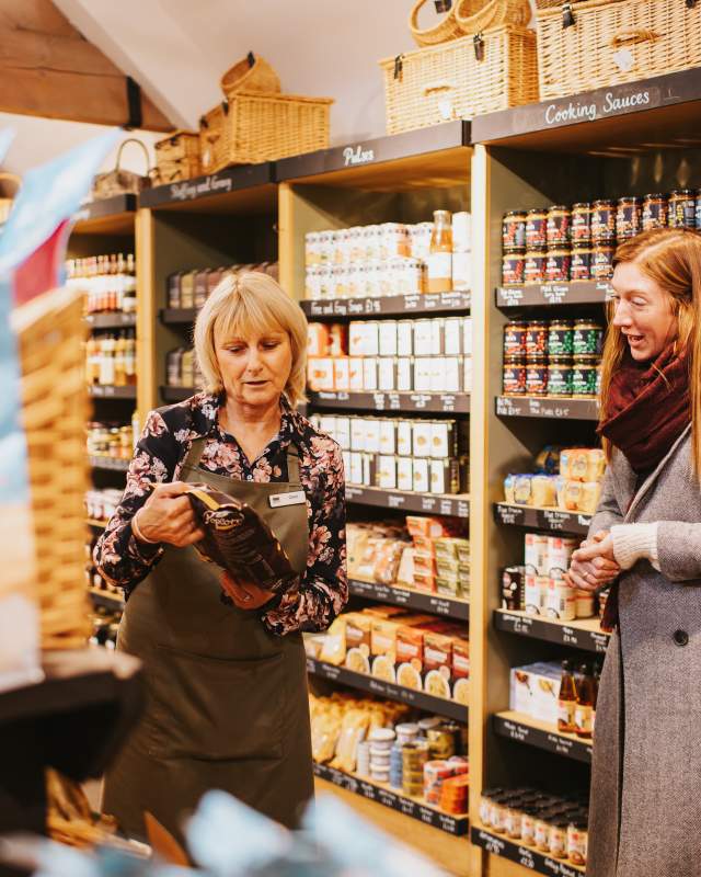A shop worker helping a customer choose local products to purchase