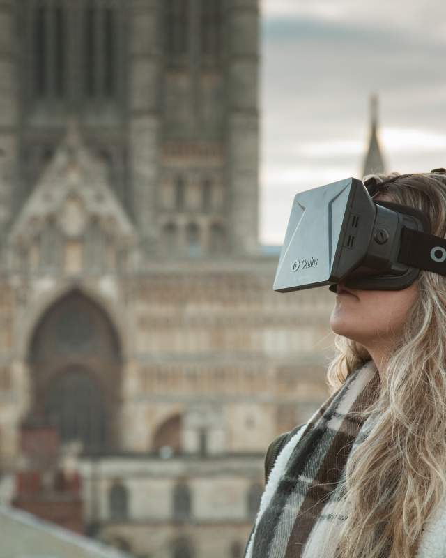A girl with a VR headset on, with Lincoln Cathedral in the background