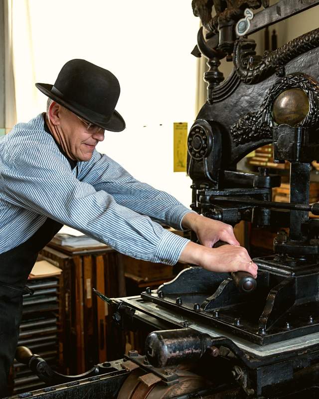 A man using a vintage printing press in the Museum of Lincolnshire Life