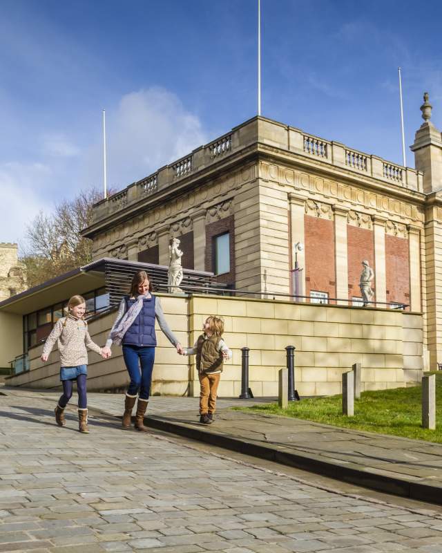 A family walking past the Usher Gallery with Lincoln Cathedral in the background