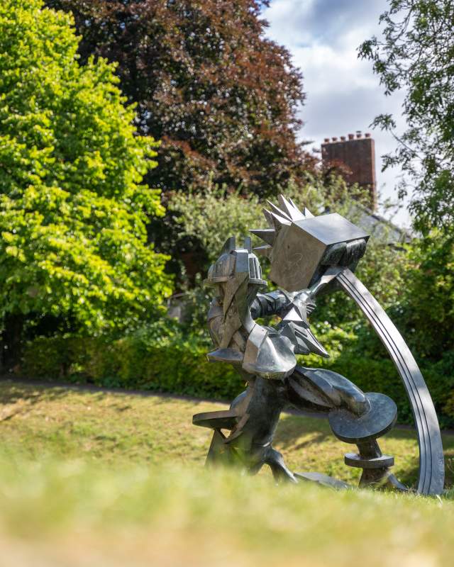 A metal sculpture of a man swinging a tool.