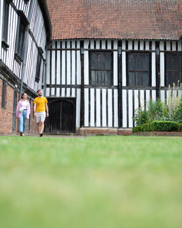 Two people walking along a path outside Gainsborough old Hall