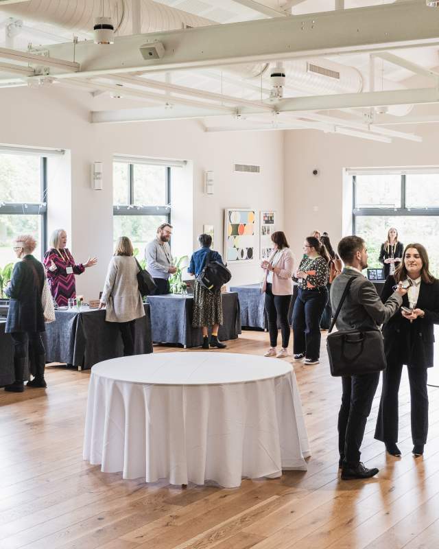 Delegates at an event talking to exhibitors around the room
