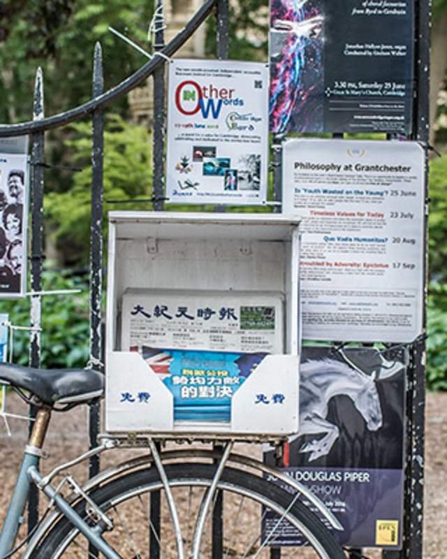 A bicycle against railings with poster adverts.