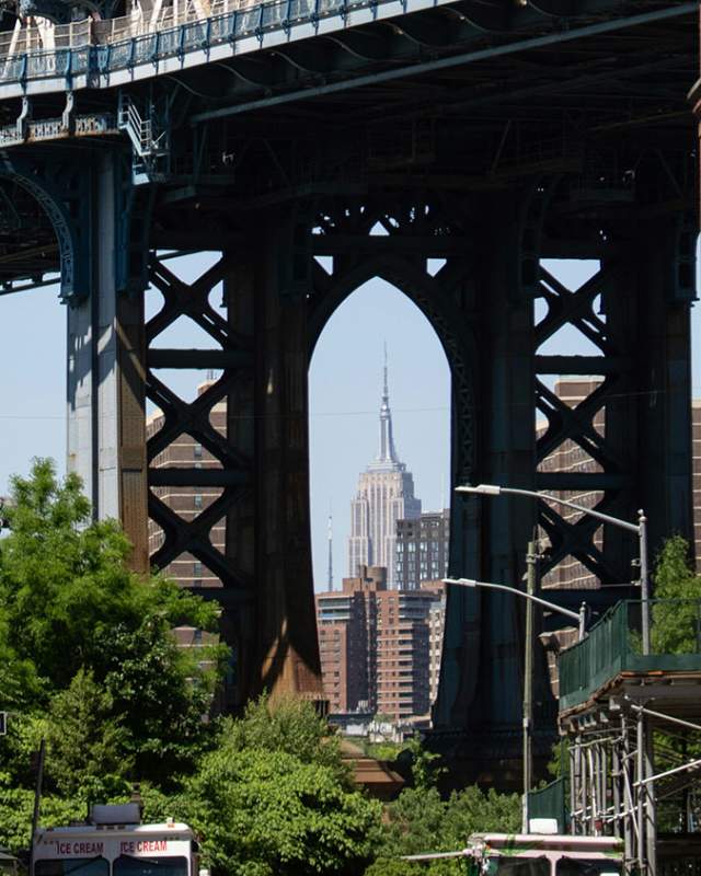 Manhattan Bridge viewed from a cobblestone street in DUMBO Brooklyn with the Empire State Building visible in the background