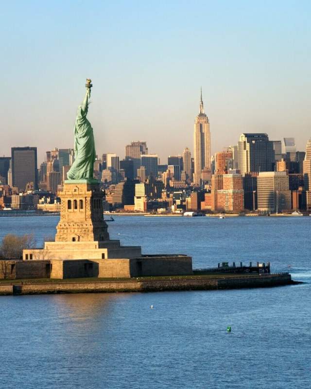Aerial view of the Statue of Liberty on Liberty Island with the Manhattan skyline and Empire State Building in the background across New York Harbor