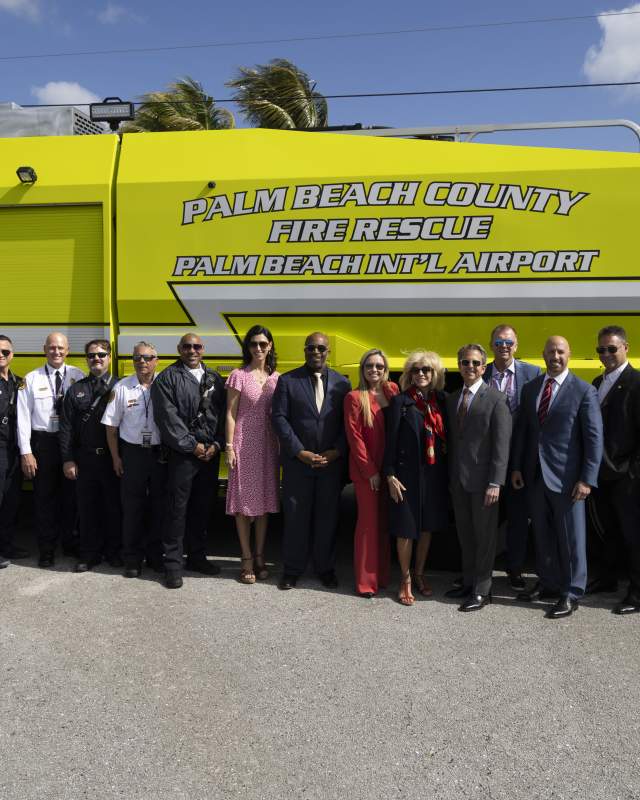Group photo of Palm Beach County Fire Rescue personnel, Department of Airports staff, county commissioners, and county administration standing together in front of the department’s Dragon fire rescue truck.