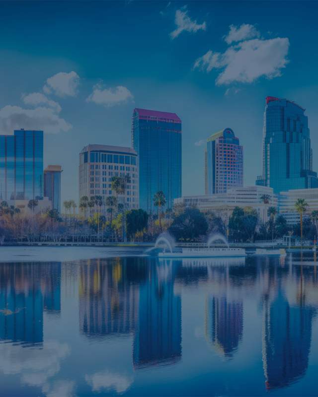 Downtown Orlando skyline reflecting with palm trees in the foreground.