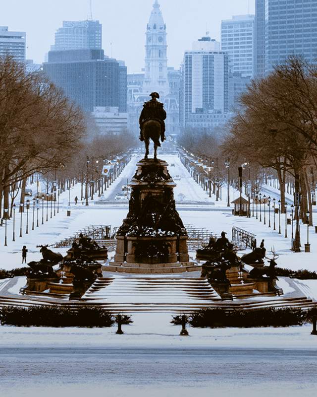Statue facing Benjamin Franklin Parkway and City Hall in Philadelphia covered in snow