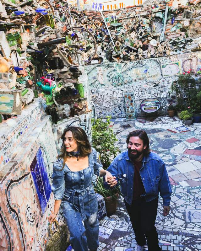 A man and woman holding hands and walking up the stairs of an outdoor mosaic museum