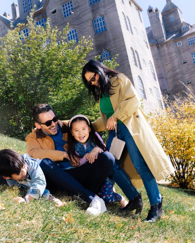 A family of four playing on a hill in front of a castle