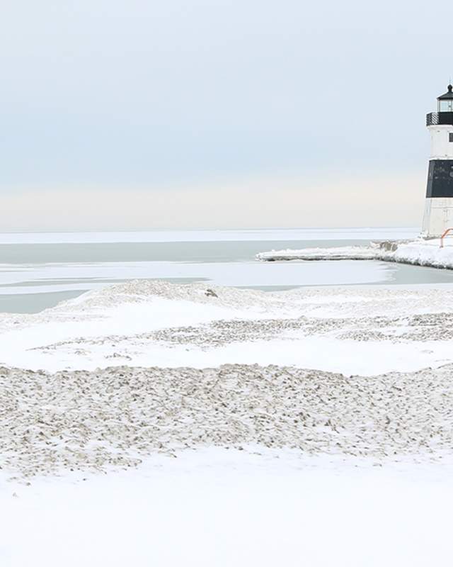 A light house sitting on a dock with snow and ice covering Lake Erie