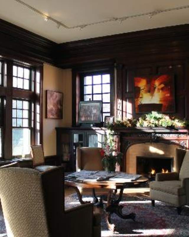 Interior of a living room with chairs and tables set in front of a fireplace