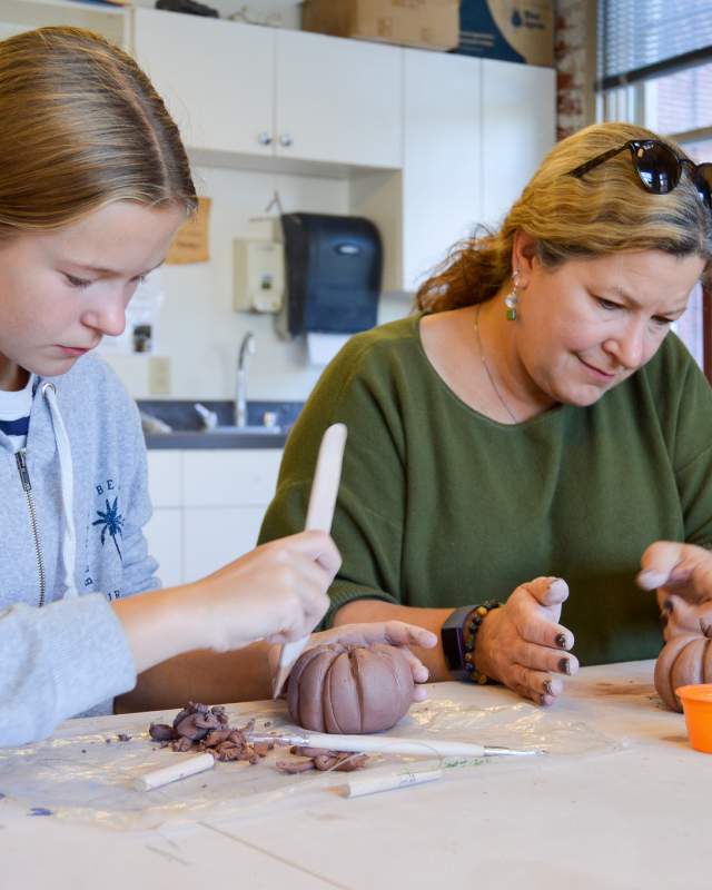 A woman and young girl, create with clay at the Goggleworks Center for the Arts