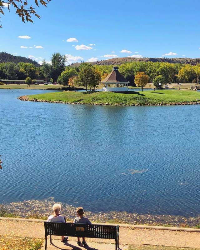 People sitting on bench looking out at Canyon Lake Park in Rapid City, SD