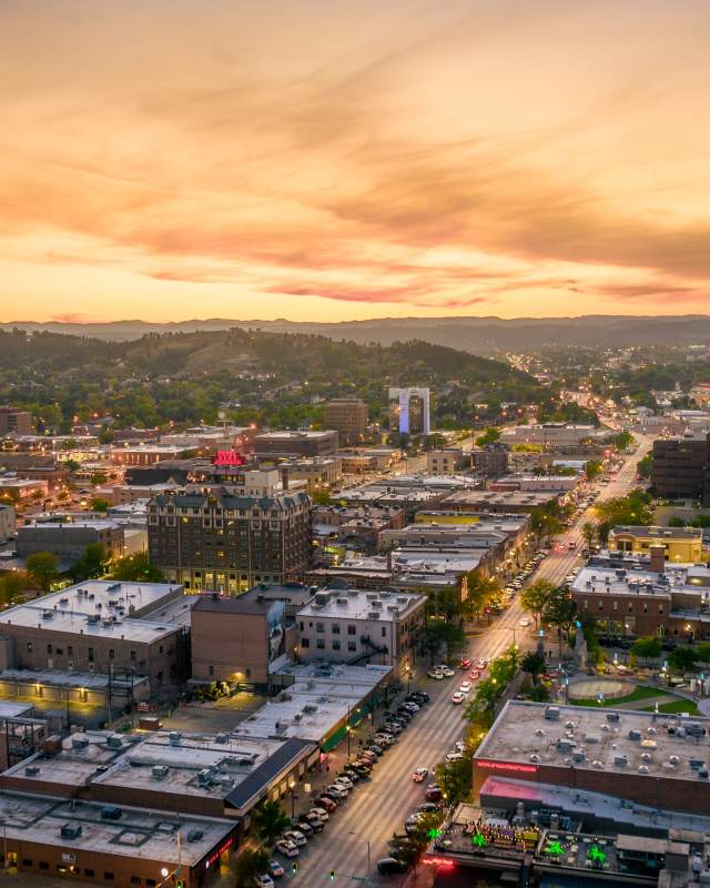 Drone shot overlooking downtown Rapid City with sunset in the background