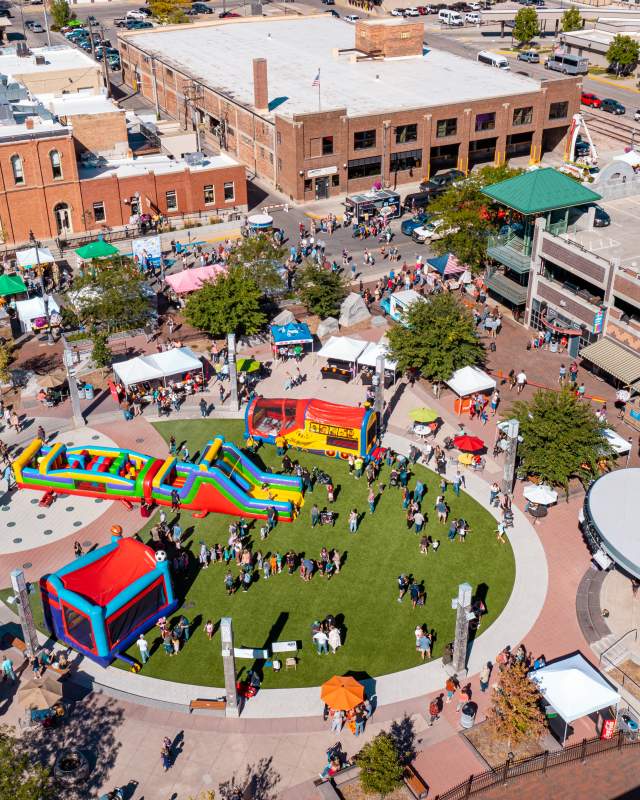 An aerial shot above Main Street Square during Pumpkin Fest, where the Square is dotted with colorful bounce houses and a large amount of people.