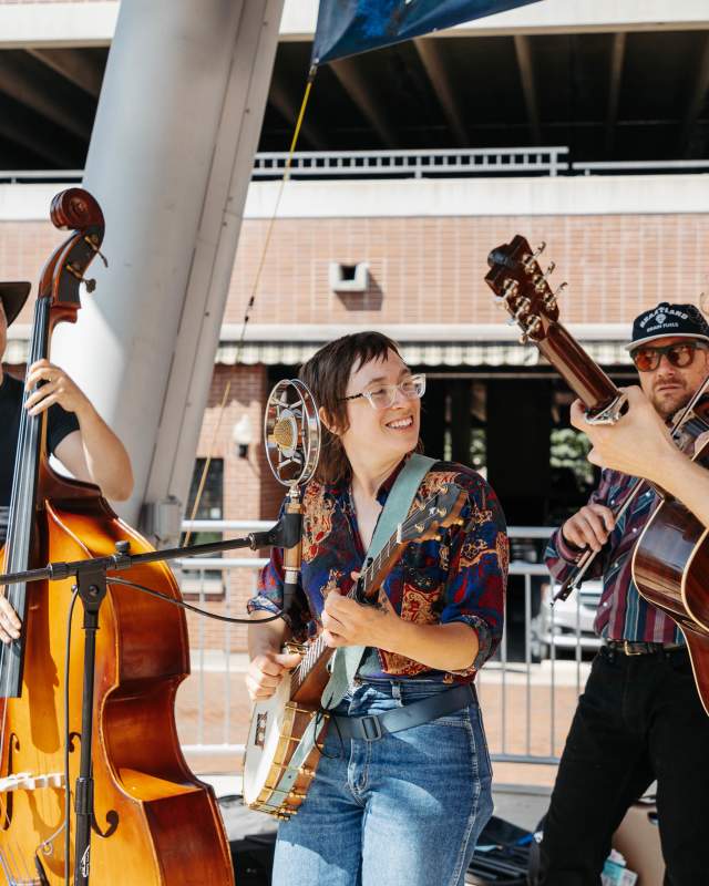 Four person band playing outdoors looking cheerful