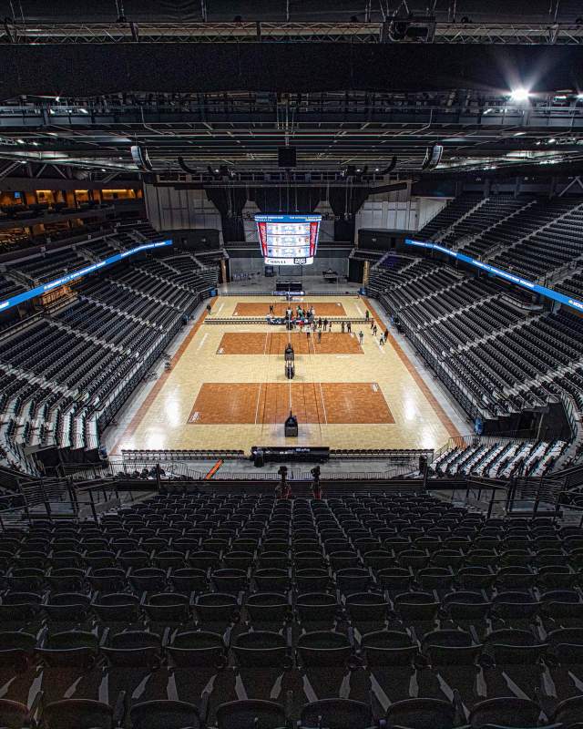 A wide shot of Summit Arena, set for a volleyball tournament with three courts set on the floor, sitting empty before the tournament begins.