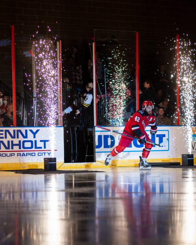 rapid city rush hockey player skating onto the ice inbetween two fireworks